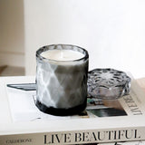 coconut wax candles in a gray glass jar with lid on stacked coffee table books