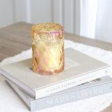 coconut wax candles in iridescent glass jar with lid on stack of coffee table books