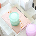 glass jars in pastel rainbow colors on home decor books on marble table