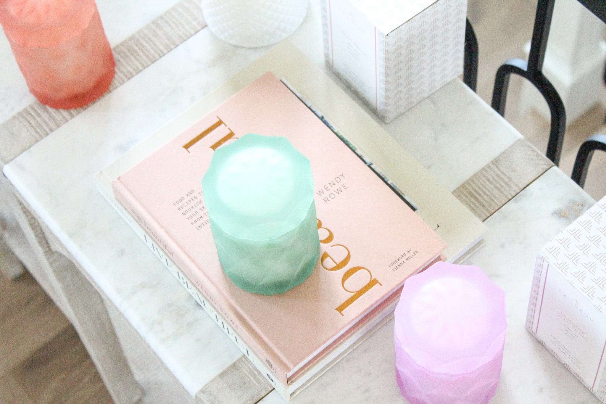 glass jars in pastel rainbow colors on home decor books on marble table