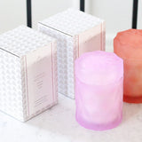 lavender lilac color and coral color glass candle jars with lids next to candle packaging 
