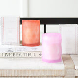 lavender lilac color and coral color glass candle jars with lids next to candle packaging on coffee table books